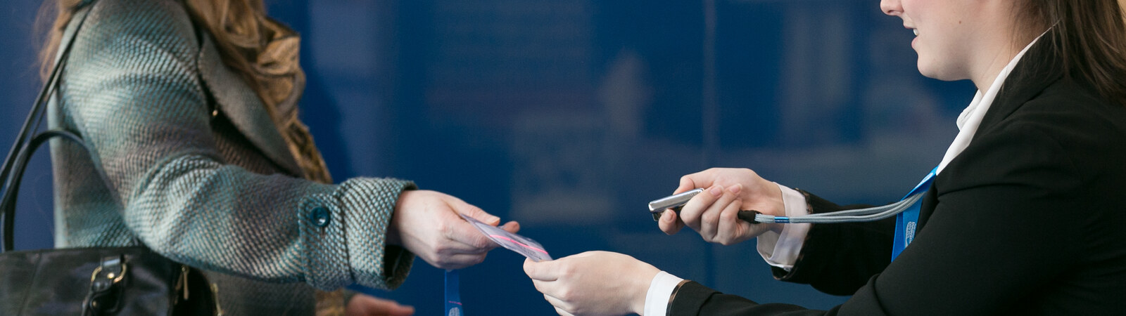 An event badge being handed to a delegate alongside a handheld scanner