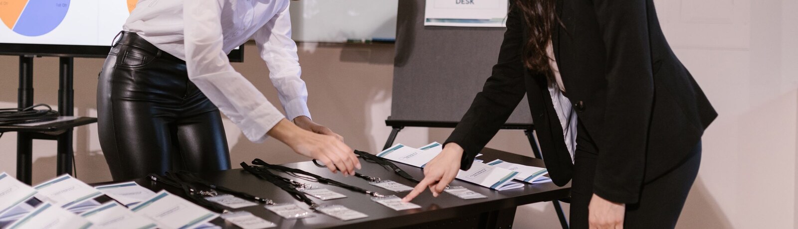 Event registration desk with printed name badges and lanyards laid out, staff preparing check-in