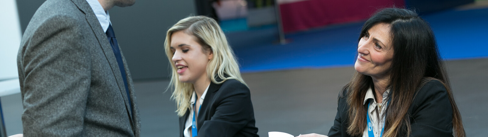 Event staff greeting delegates wearing lanyards on a conference floor