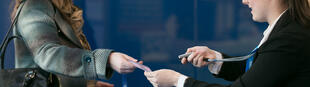 An event badge being handed to a delegate alongside a handheld scanner