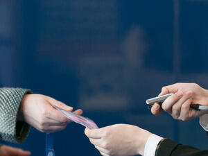 An event badge being handed to a delegate alongside a handheld scanner