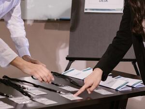 Event registration desk with printed name badges and lanyards laid out, staff preparing check-in
