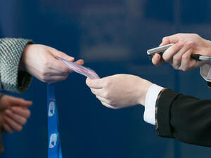 Event staff handing a printed badge and lanyard to an attendee at a registration desk