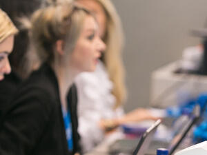 Event registration staff checking in delegates at a desk with badge printers