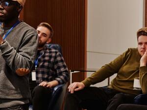 Panel speakers at a conference wearing printed name badges on lanyards